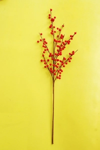 Close-up of red artificial berry branches with glossy finish on a yellow background