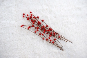Macro shot of artificial red berry branches for Christmas decor on white plush background