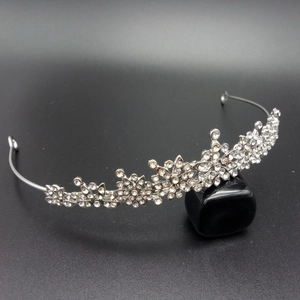 Detailed view of silver bridal tiara with floral rhinestone patterns on a stone support