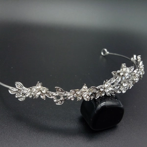 Detail of silver bridal crown featuring crystal flowers and leaves on a gradient background