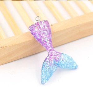 Glittery gradient purple resin mermaid tail pendant with metal loop on white background