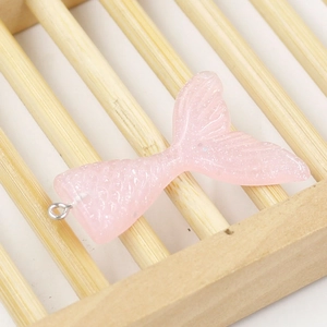 Detailed view of pink resin mermaid tail charm with glitter finish on bamboo stand