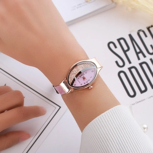 Detail of rose gold oval watch featuring moving rhinestones on a pink sand dial