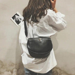 Minimalist black leather crescent chest bag with silver zippers shown on a model