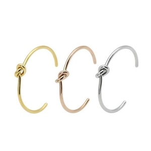 Detailed view of three minimalist knot cuffs in gold, silver, and rose gold finishes