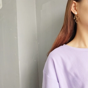 Detail of model wearing gold horse-head stud earrings with round white pearls