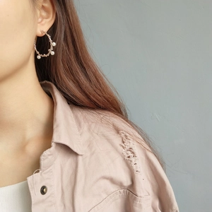 Detail of 925 sterling silver hoop earrings with white pearls on a model
