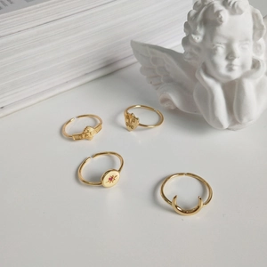 Detailed shot of four gold adjustable rings with baby, heart, and star motifs on white background