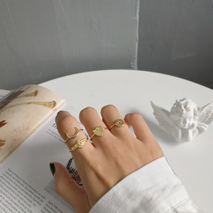 Close-up of gold ring set featuring moon, heart shield and red ruby star on model's hand