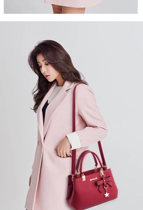 Detail of red pebbled leather handbag with bow charm paired with pink textured coat