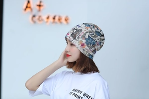 Detail view of a soft printed turban hat worn by a model in a bright coffee shop setting