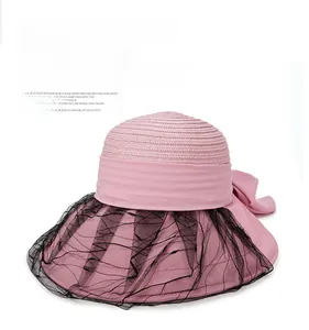 Detail of pink straw sun hat featuring elegant black lace mesh and a large bow decor