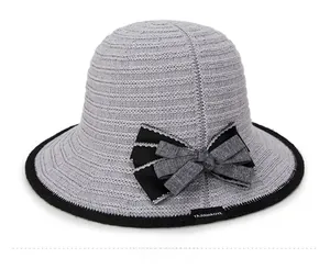 Macro view of grey knitted sun hat showing bow detail and woven label texture