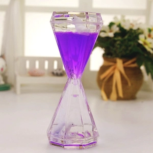 Macro detail of diamond shaped liquid hourglass with a miniature penguin figure and purple oil