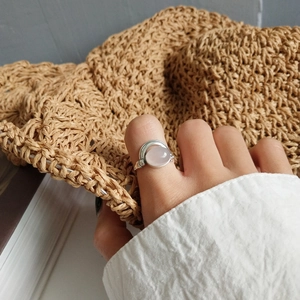 Detail of 925 silver ring with pink rose quartz on finger in a natural setting