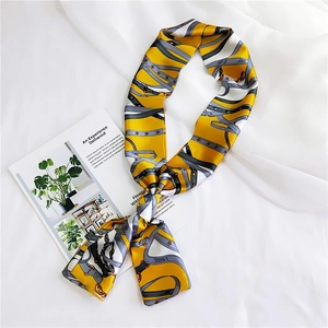 Elegant yellow silk scarf with chain and belt print tied in a knot on white fabric