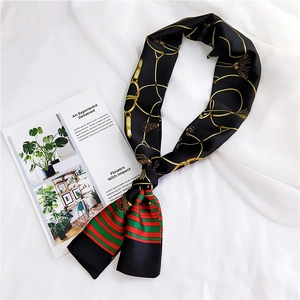 Close-up of black silk scarf with gold chain patterns and green-red striped detail