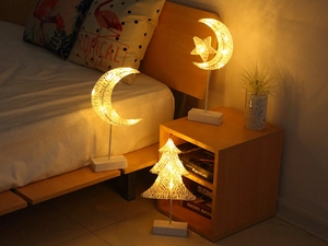 Cozy bedroom setting with crescent moon and Christmas tree rattan LED lamps on wooden bases