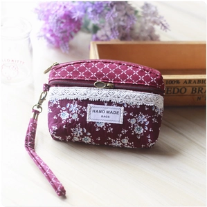Detail of handmade deep burgundy floral coin purse with lace trim on a rustic wooden table