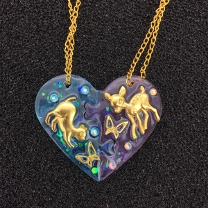 Détail de colliers puzzle cœur avec pendentifs en résine, feuilles dorées d'animaux et paillettes
