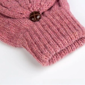 Gros plan sur les gants en laine rose montrant la maille douce et le bouton rétro brun