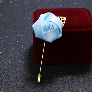 Detail of light blue satin rose brooch with gold metal leaf on black glitter background