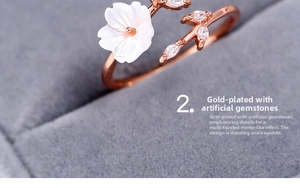 Close-up of rose gold floral ring with white shell petal and marquise-cut gemstones