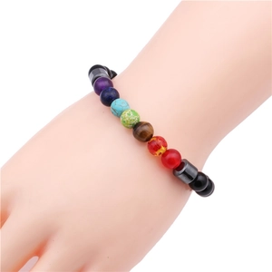 Close-up of a chakra bracelet with colorful natural stones and black hematite beads on wrist