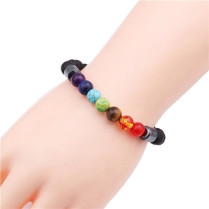 Close-up of a colorful chakra lava stone beaded bracelet on a wrist against white background