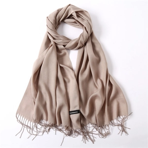 Macro shot of light beige cashmere scarf showing soft texture and fine fringe details
