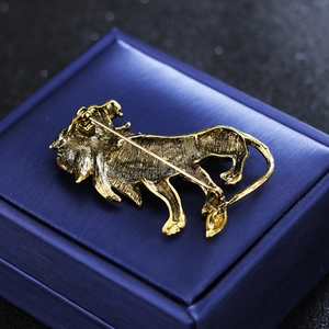 Golden lion brooch with pin back closure displayed on a blue textured jewelry box