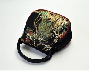 Close-up of intricate peacock embroidery and golden sequins on black fabric handbag