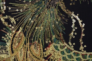Macro shot of colorful peacock feather embroidery and gold sequins on black fabric
