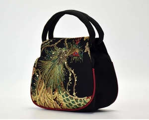 Detailed close-up of a peacock embroidery with golden sequins on a black handbag