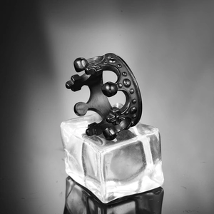 Macro shot of a black titanium steel crown ring with cross motifs on a glass block
