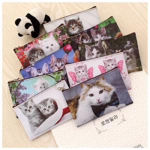 Mini cat print coin purses with zipper and keychains on a light wooden table