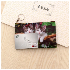 Close-up of a slim cat coin purse with zipper and keyring shown next to a bank card