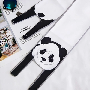 Close-up of cute panda scarf with wash care label, magazine and sunglasses setup