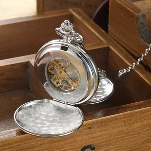Detail of silver mechanical pocket watch showing internal golden gear mechanism and chain