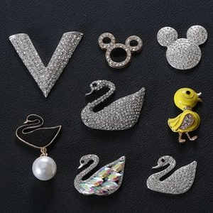 Macro detail of alloy brooches with sparkling crystals and pearls on black leather