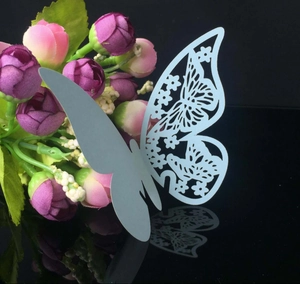Detail view of laser-cut butterfly place card in light blue on decorative flowers