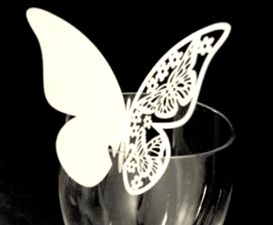 Macro shot of white laser-cut butterfly place card for wedding wine glass decoration