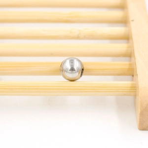 Polished silver stainless steel spacer beads on a bamboo tray for DIY jewelry making