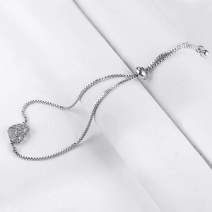 Détail d'un bracelet ajustable en argent avec un pendentif cœur serti de zircons