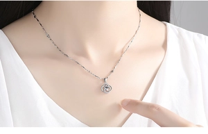 Detail of silver clover pendant with rotating crystal on a twisted chain necklace