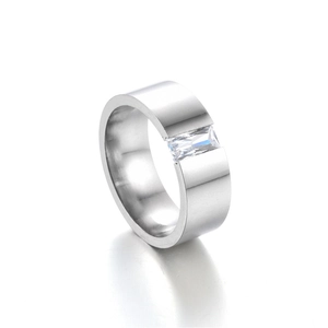 Close-up of wide band metal ring featuring a rectangular cut clear zircon stone