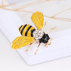 Close-up detail of a gold bee brooch with yellow enamel wings and sparkling rhinestones
