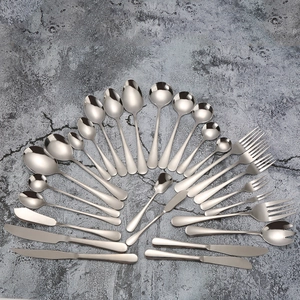 Flat lay of complete stainless steel cutlery set with spoons, forks and knives on grey surface