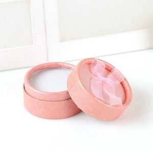 Pink round jewelry gift box with textured finish and a matching ribbon bow on top