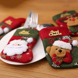 Christmas silverware holders featuring Santa and reindeer on a wooden dining table